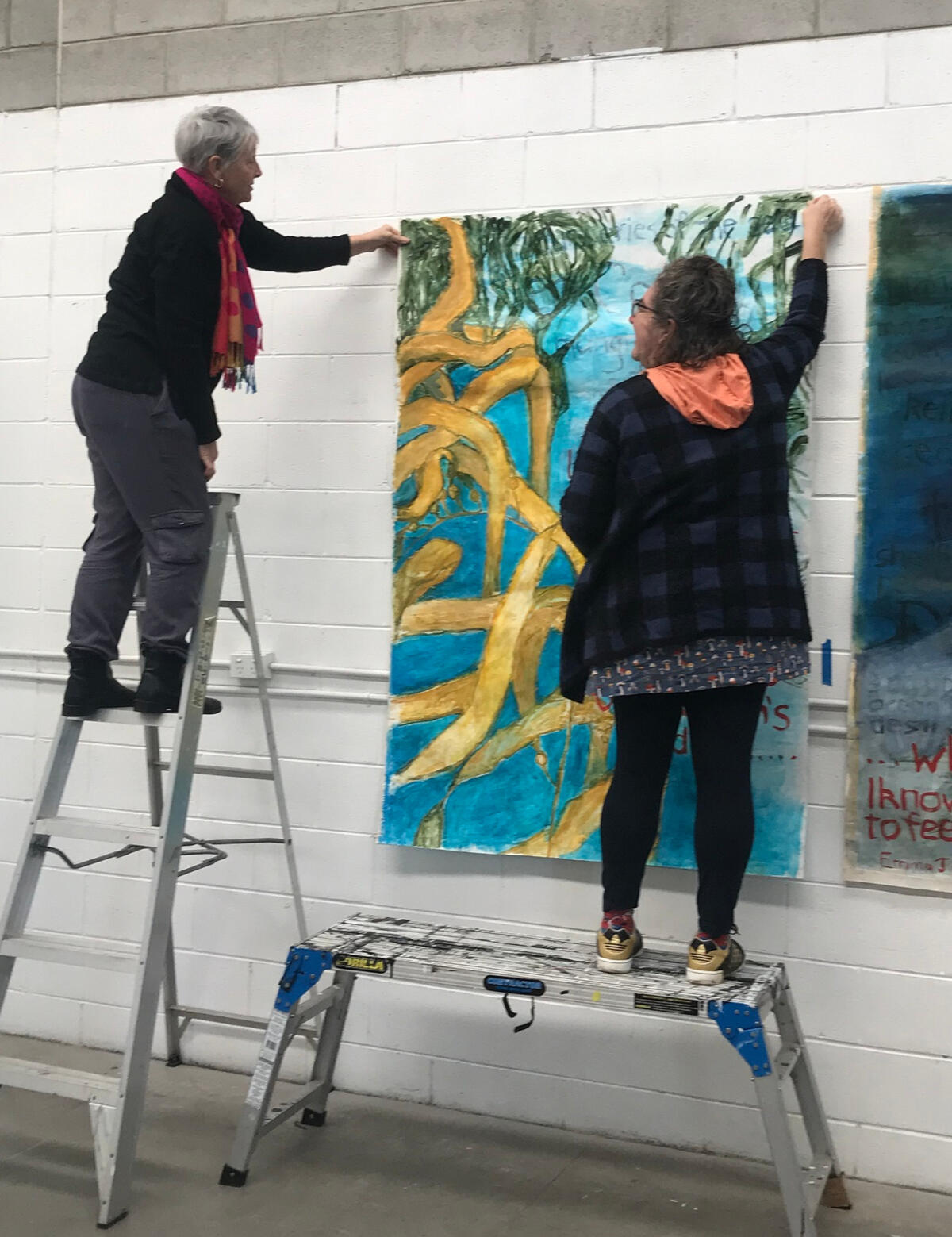 members of Lucy Goosey Feminist Art Collective hanging a painting